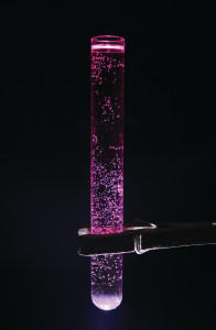 A test tube with some pink fluid and bubbles